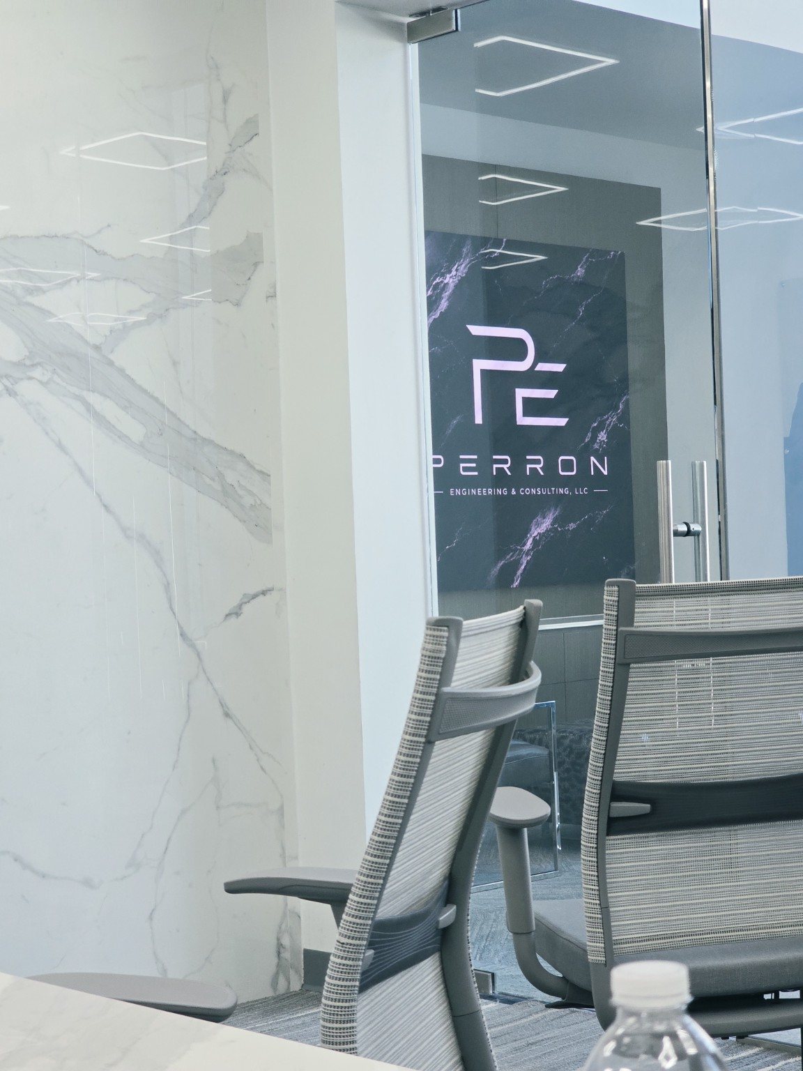 Perron Engineering logo displayed on the VUE video board in the LRC lobby, seen through the glass door of the conference room