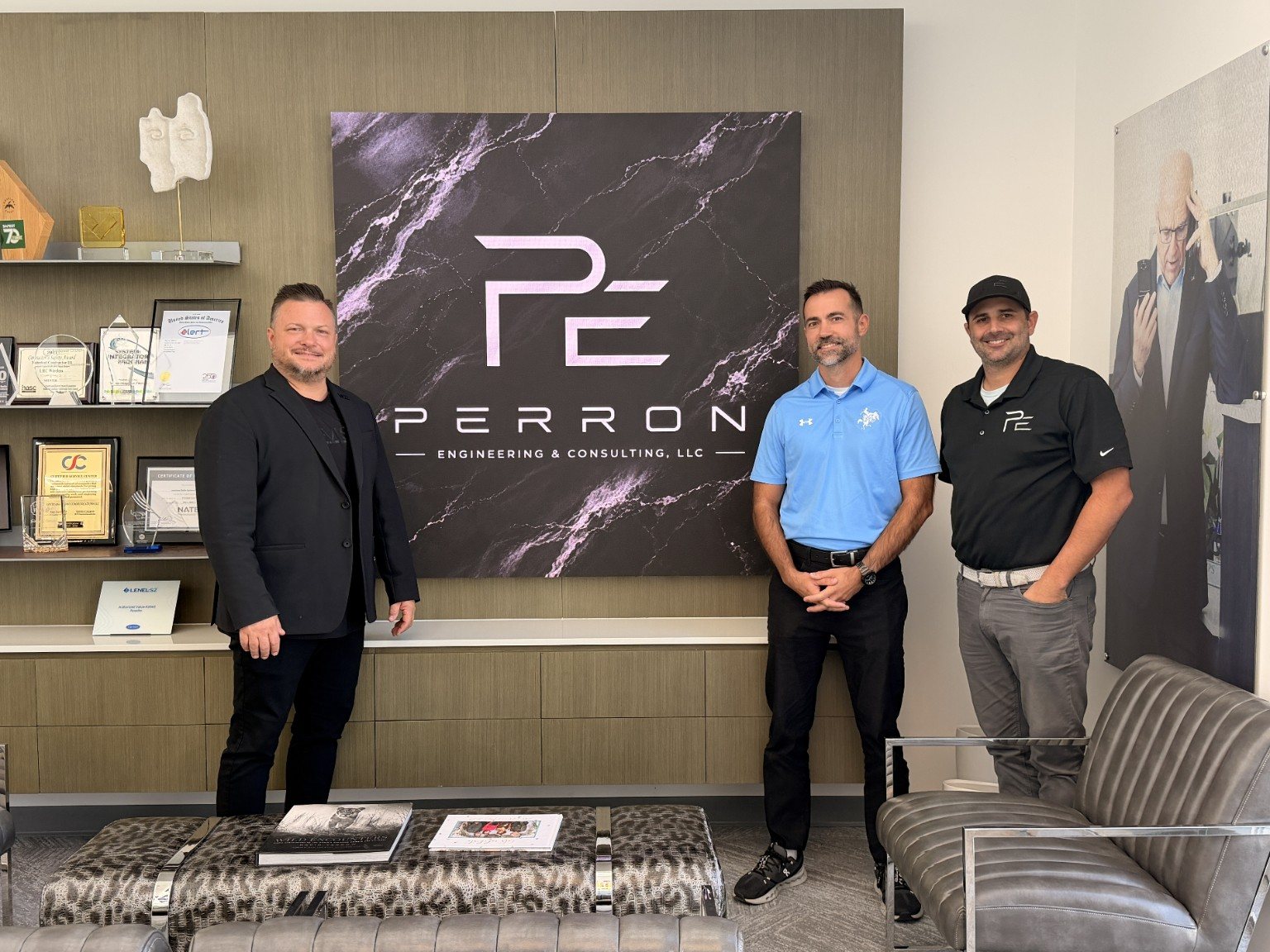 Donnie Culpepper, Garrett Vincent and Dustin Perron standing in front of a VUE LED video display showing the Perron Engineering logo in the LRC lobby